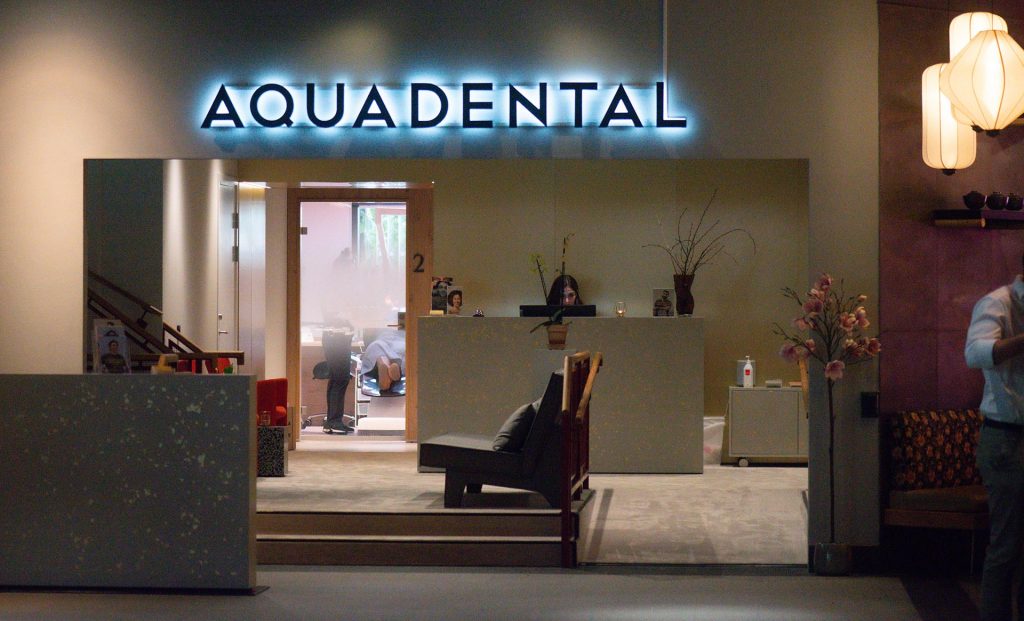 En blå lysande skyltdesign som lyder aquadental. 